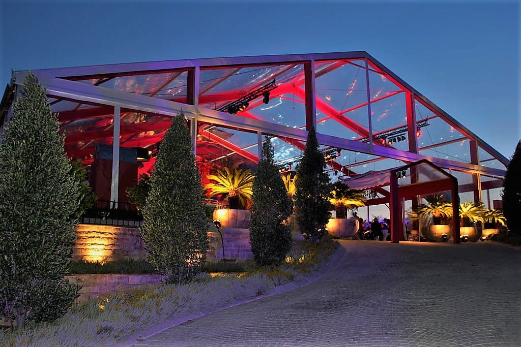 Red steel-frame tent structure with outdoor lighting at night.