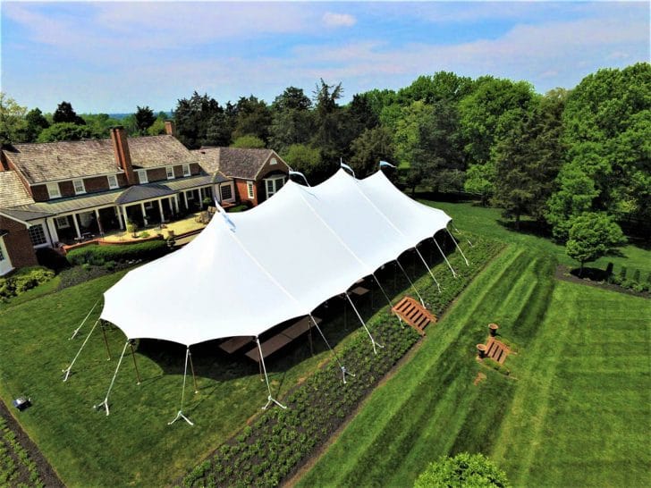 Large white sailcloth event tent set up in a backyard for a formal outdoor event. Ideal for weddings and corporate gatherings.