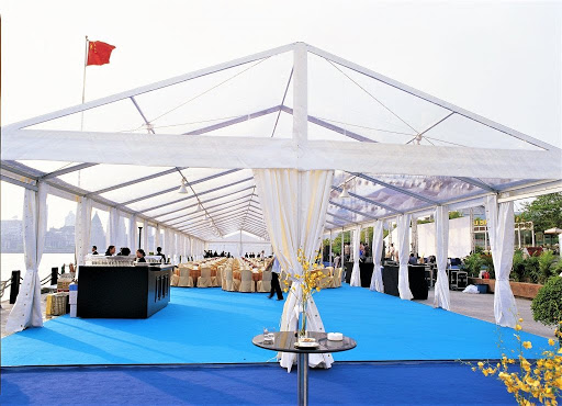 Clear-top white event tent with draped fabric and blue flooring.