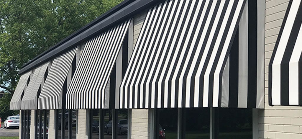 Commercial building with angled black-and-white awnings along windows.