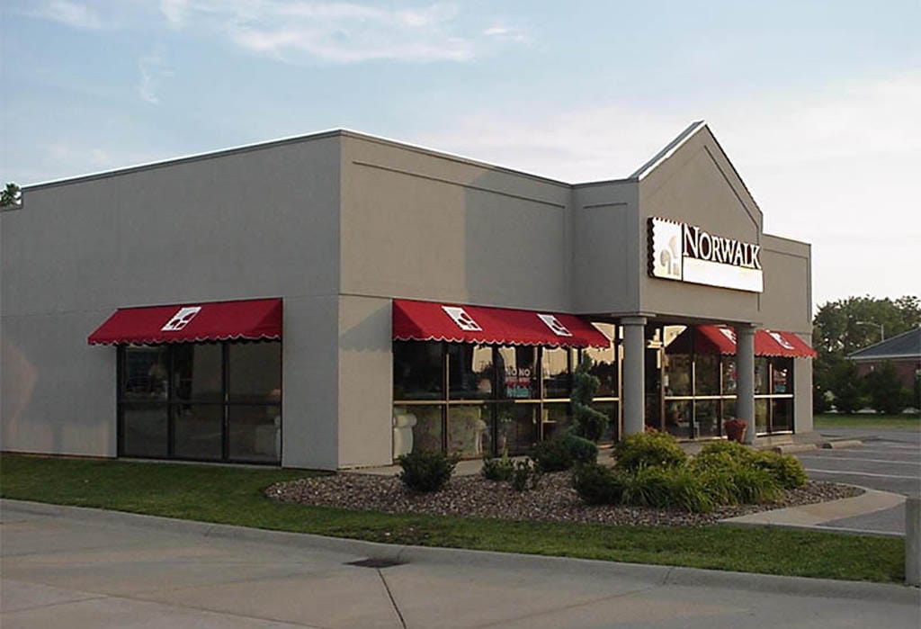 Commercial building with red awnings over entrance windows and signage.