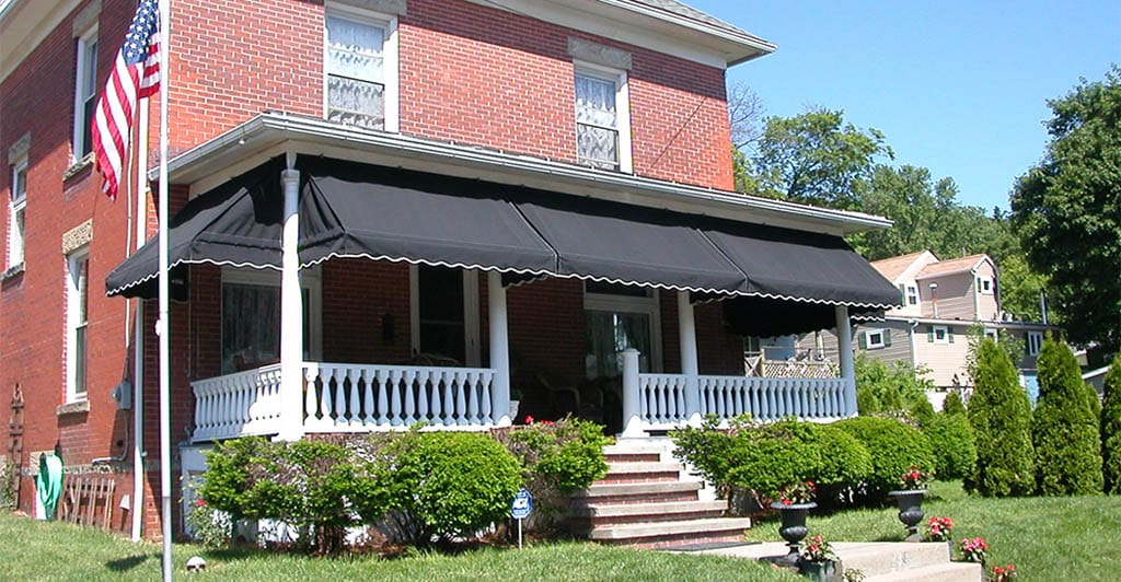 Classic house with black fabric awning covering the front porch.