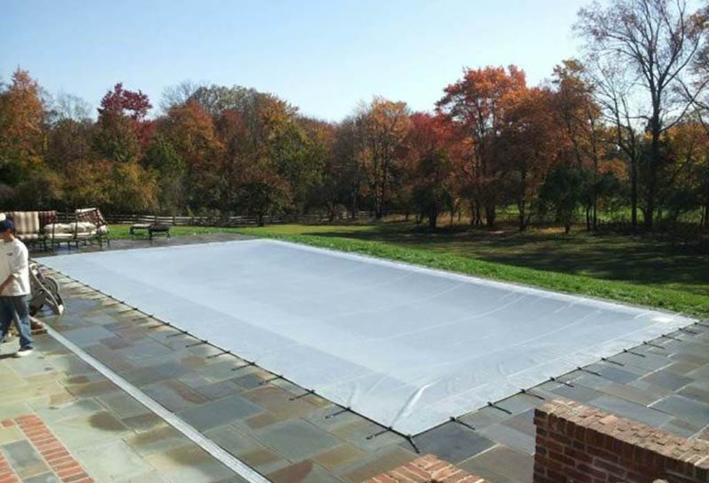 Rectangular pool covered with a light gray mesh safety cover.