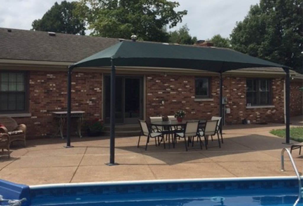 Backyard patio with green awning providing shade over a dining table.