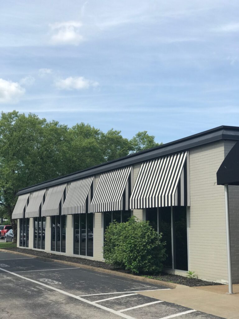 Commercial building with striped black and white awnings along the exterior.