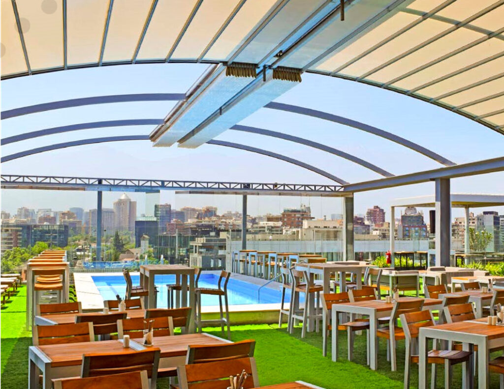 Modern rooftop restaurant with a retractable pergola, offering stylish outdoor dining with a city skyline view. Ideal for commercial patio covers.