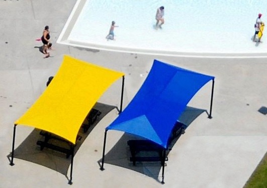 Two poolside lounge chairs shaded by yellow and blue canopy structures.