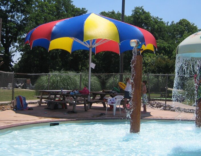Colorful blue, yellow, and red canopy umbrella shading a splash pad area.