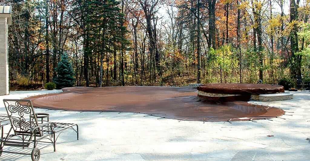Another brown pool cover surrounded by trees.