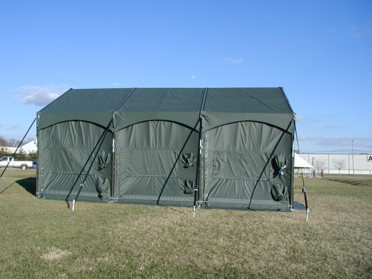 Green military-style tent on an open field.