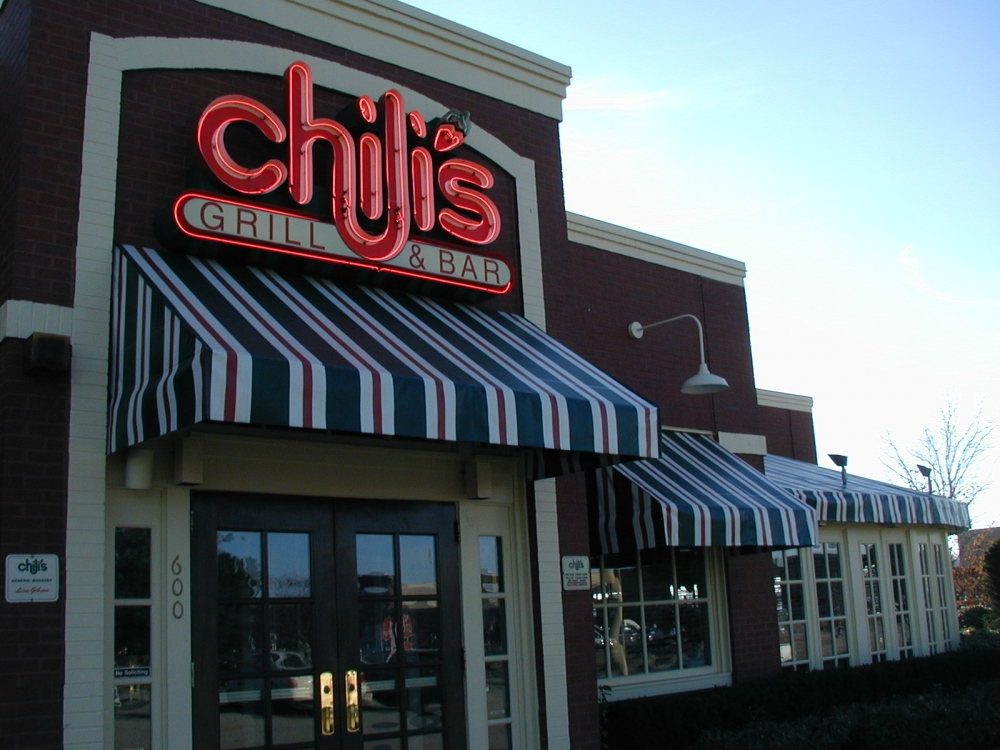 Restaurant entrance with striped awning and Chili’s sign.