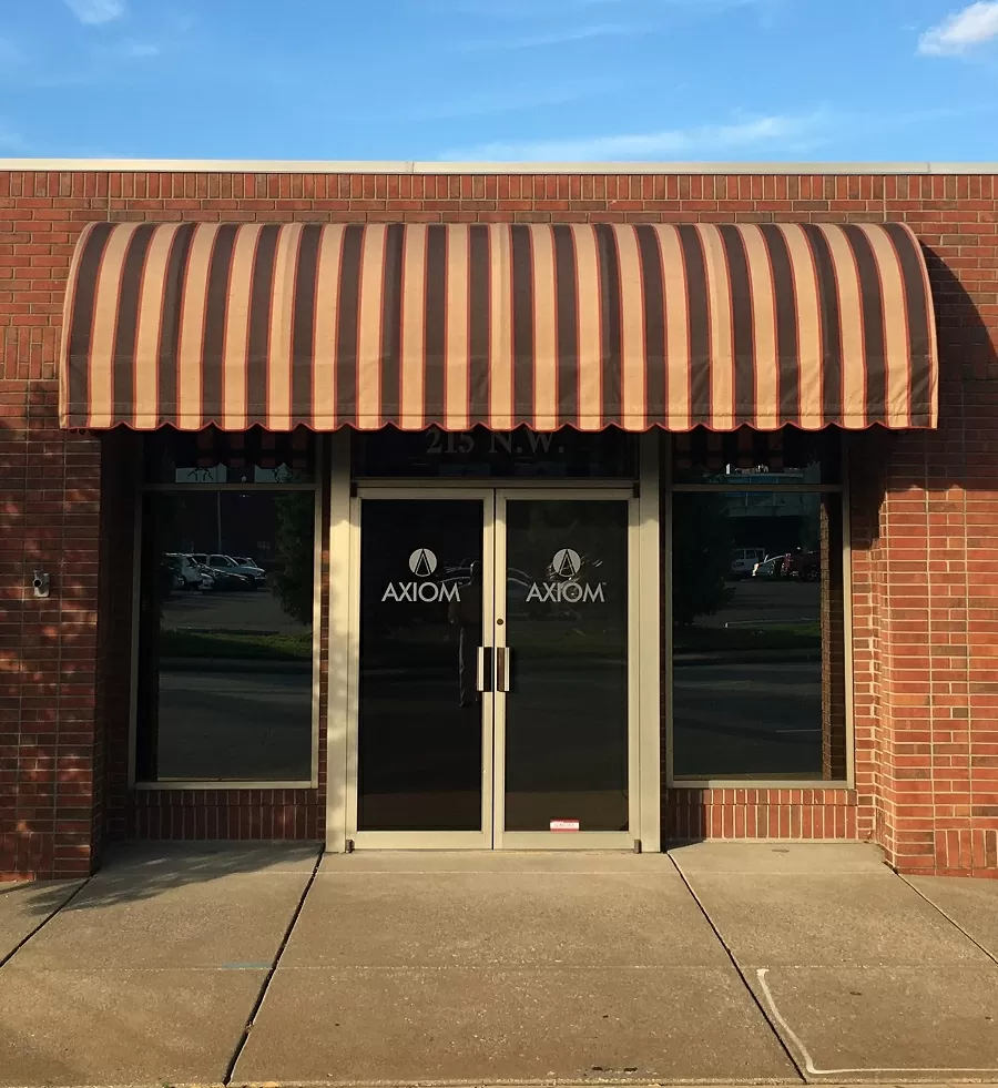 Brown striped fabric awning above double glass entry doors.