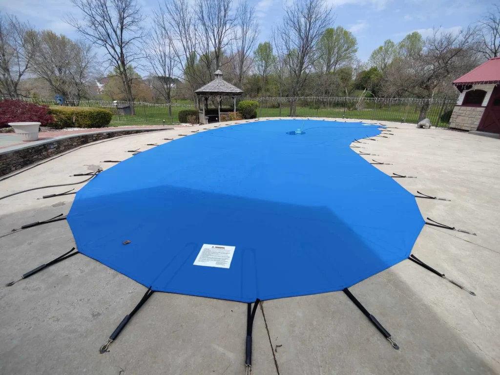 Circular pool secured with a bright blue mesh safety cover.
