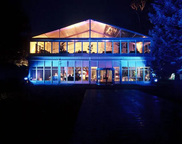 Glass-walled clearspan event tent illuminated at night with blue lighting