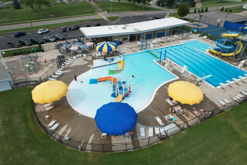 Aerial view of a large outdoor pool complex with multiple shade canopies and umbrellas.