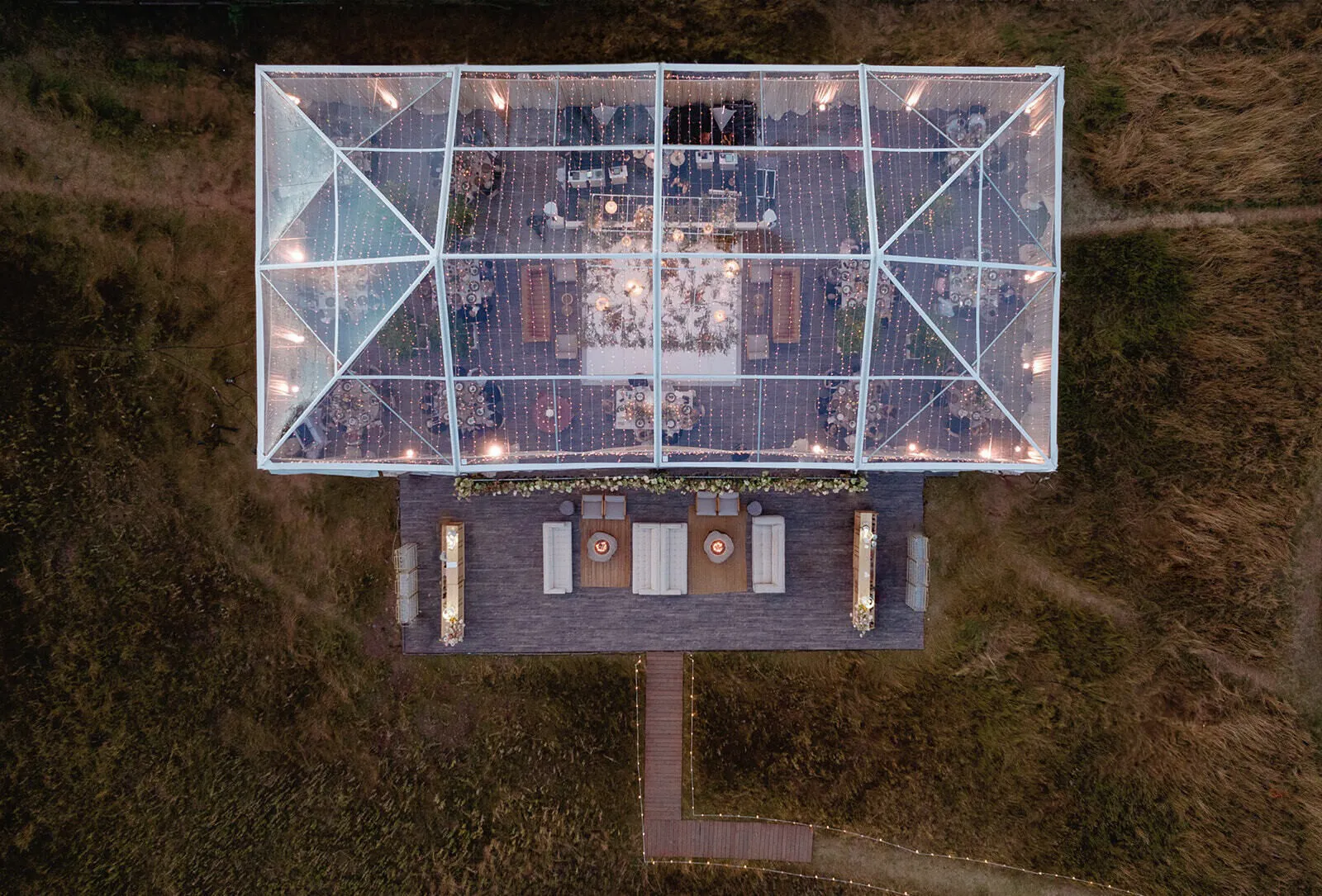 Aerial view of a transparent clear-top tent covering a formal event setup.