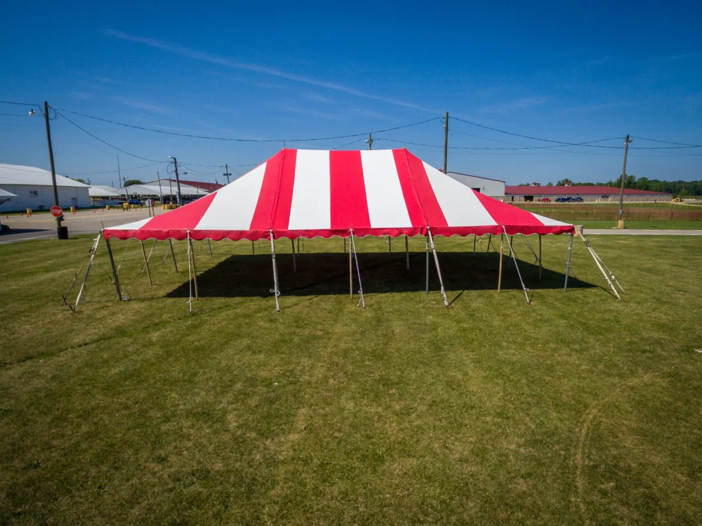 Red and white striped Anchor Industries rental tent on grass field