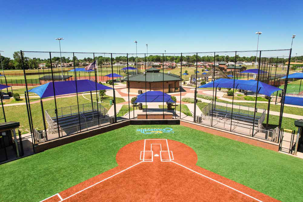 Baseball field with spectator shade structures behind home plate.