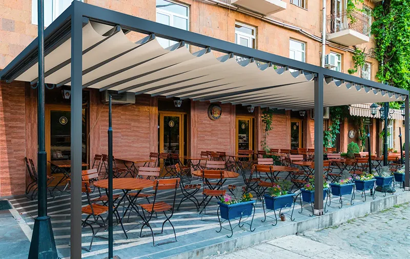 Outdoor restaurant patio covered by a retractable pergola.