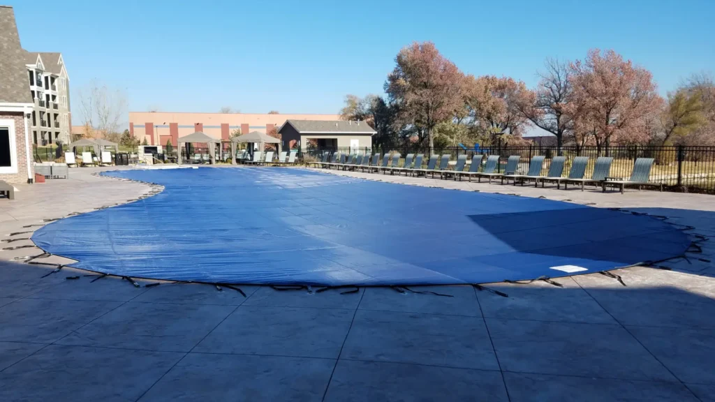 Blue solid pool cover – community pool with solid blue safety cover installed.