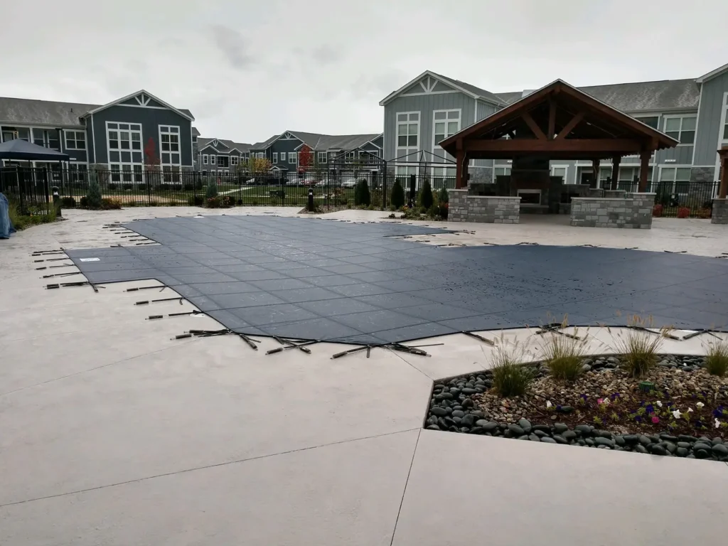 Large pool with gray cover – suburban home with rectangular pool secured by gray mesh safety cover.