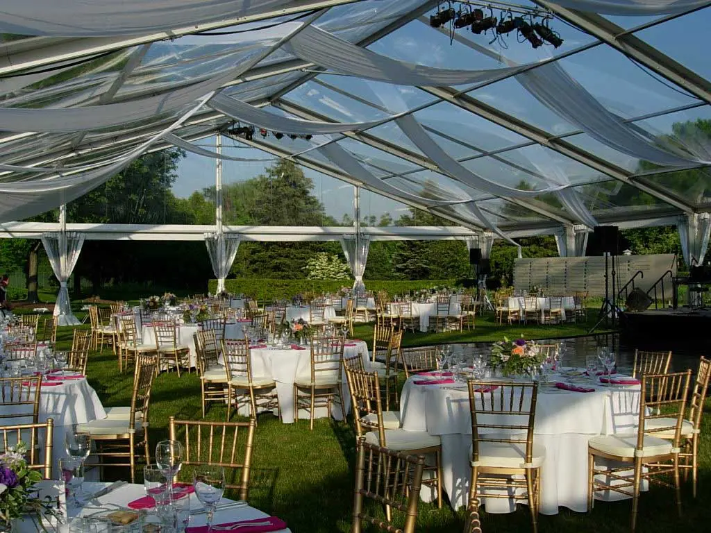Clear top event tent with elegant dining setup and chandeliers