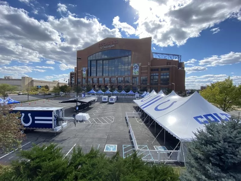 Large white event tents outside modern building with signage.