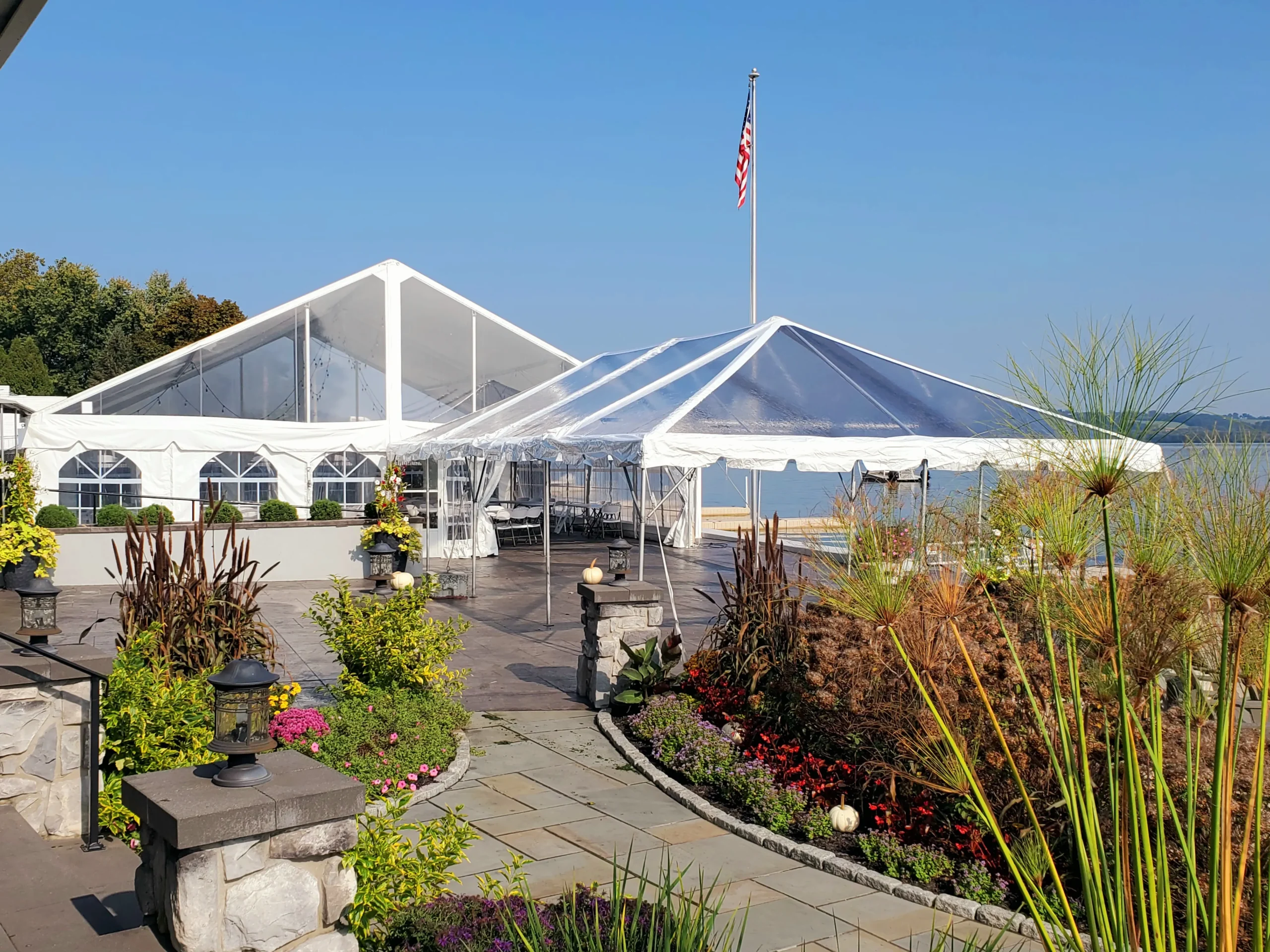 Clear-top tent beside a building with landscaped garden and blue sky.