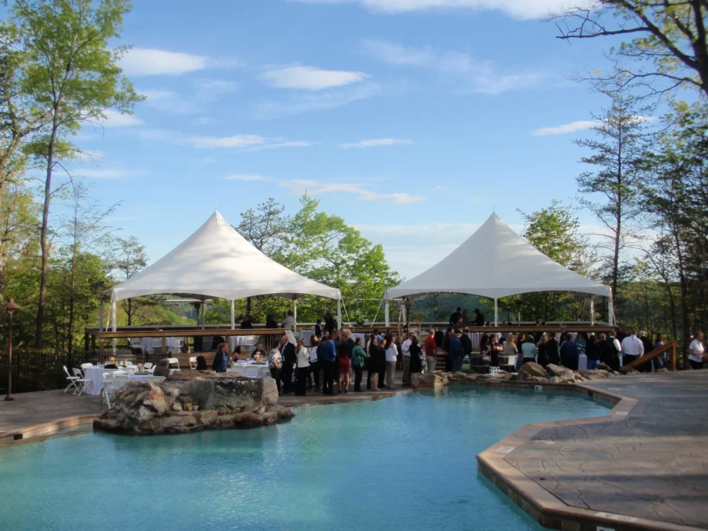 Event tents set up beside a pool with guests gathering nearby.