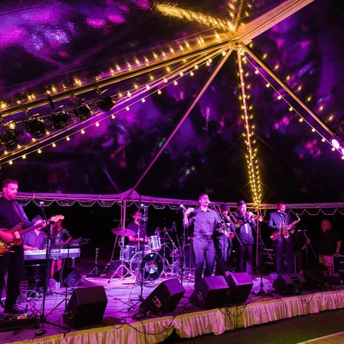 Nighttime event under a tent with purple lighting and string lights.