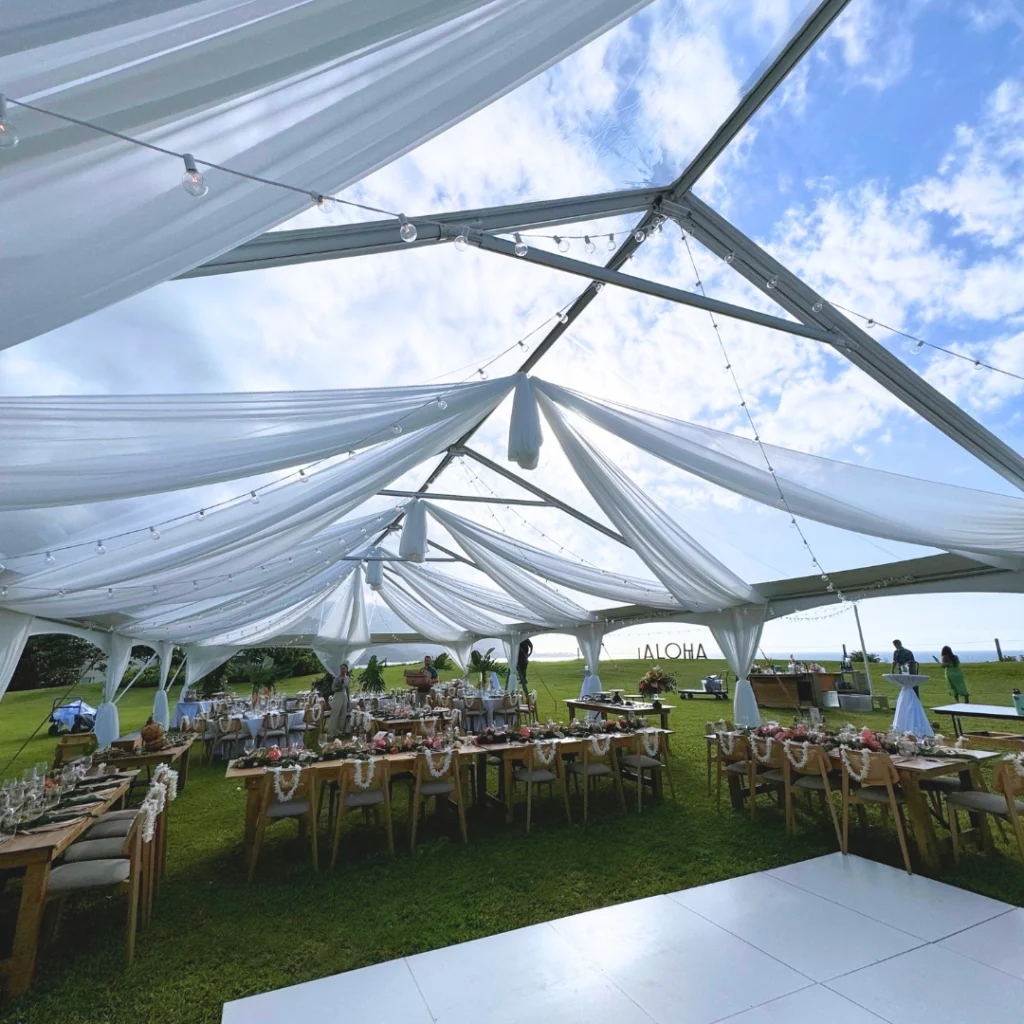 Inside view of a transparent frame tent showing the sky and white draping.