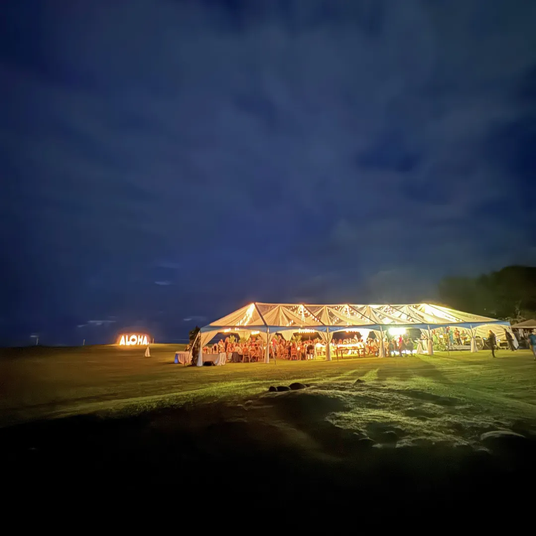 Large illuminated tent at night in an open field setting.