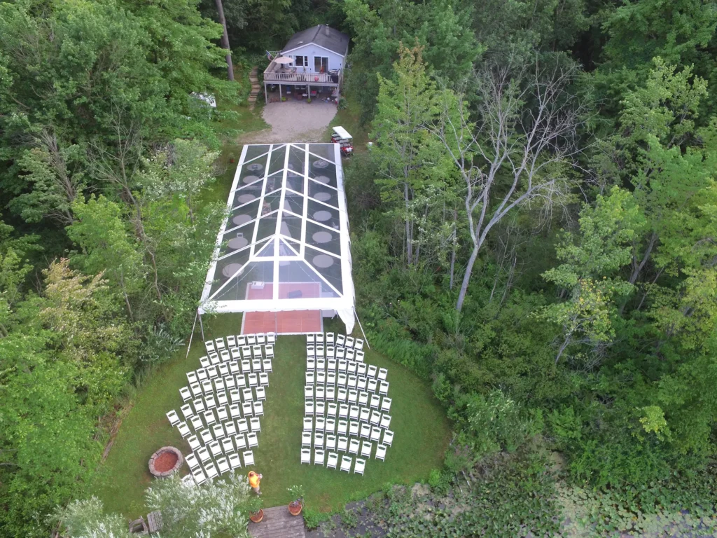 Aerial view of a clear structure extending from a house into a forest.