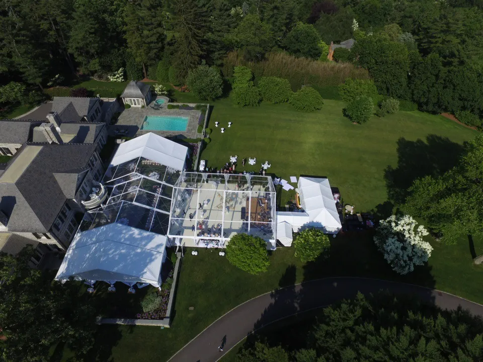 Aerial view of a large event tent setup on a green lawn.
