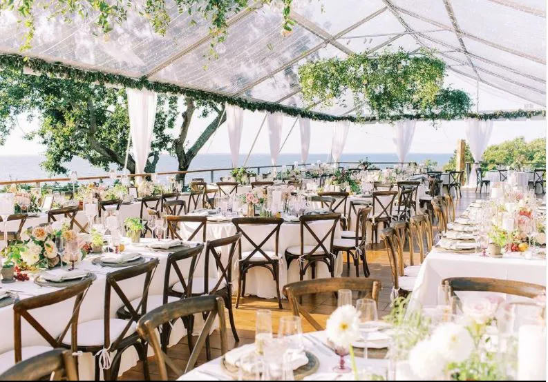 Clear-top tent dining area surrounded by trees and floral décor.