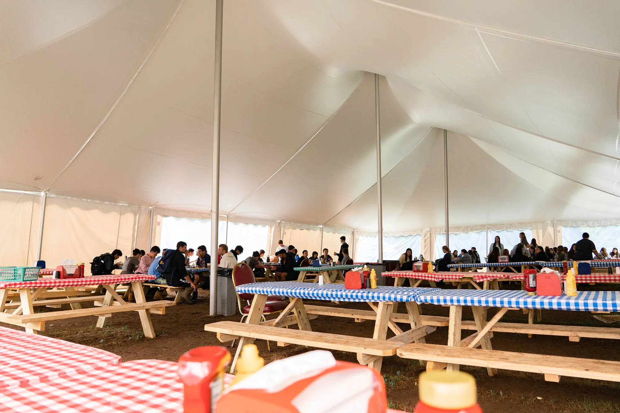 Interior view of a white tent with guests seated at long tables.